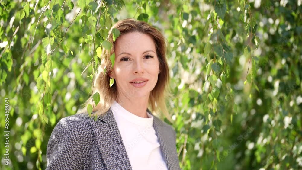 attractive woman is smiling broadly in park in sunny weather, portrait near birch tree attractive woman is smiling broadly in park in sunny weather, portrait near birch tree