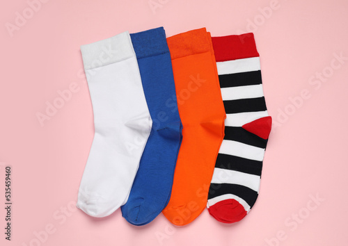 Different colorful socks on pink background  flat lay