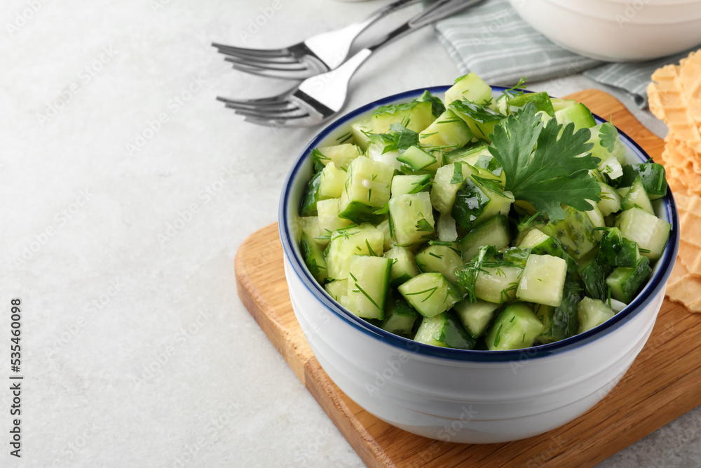 Bowl of delicious cucumber salad served on light table, closeup. Space for text Bowl of delicious cucumber salad served on light table, closeup. Space for text