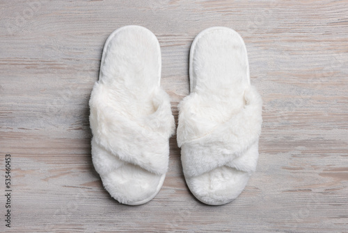 Pair of soft slippers on white wooden floor, top view