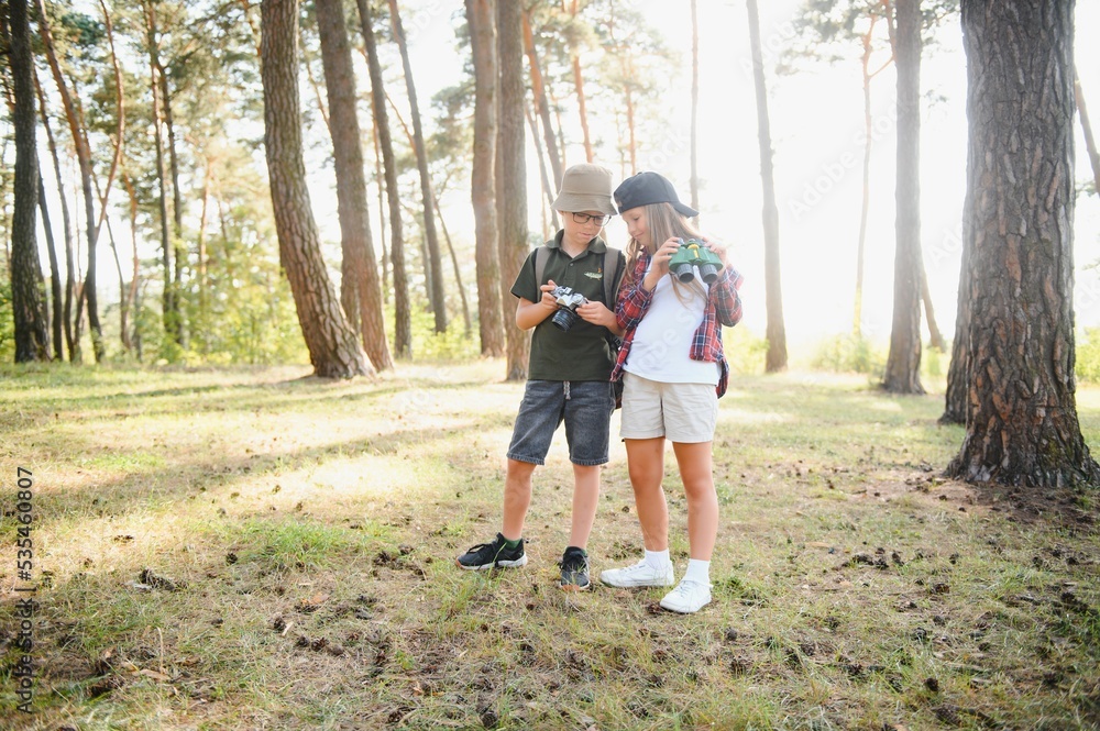 Happy excited school children with backpacks in casual clothes enjoying walk in forest on sunny autumn day, two active kids boy and girl running and playing together during camping trip in nature. Happy excited school children with backpacks in casual clothes enjoying walk in forest on sunny autumn day, two active kids boy and girl running and playing together during camping trip in nature.
