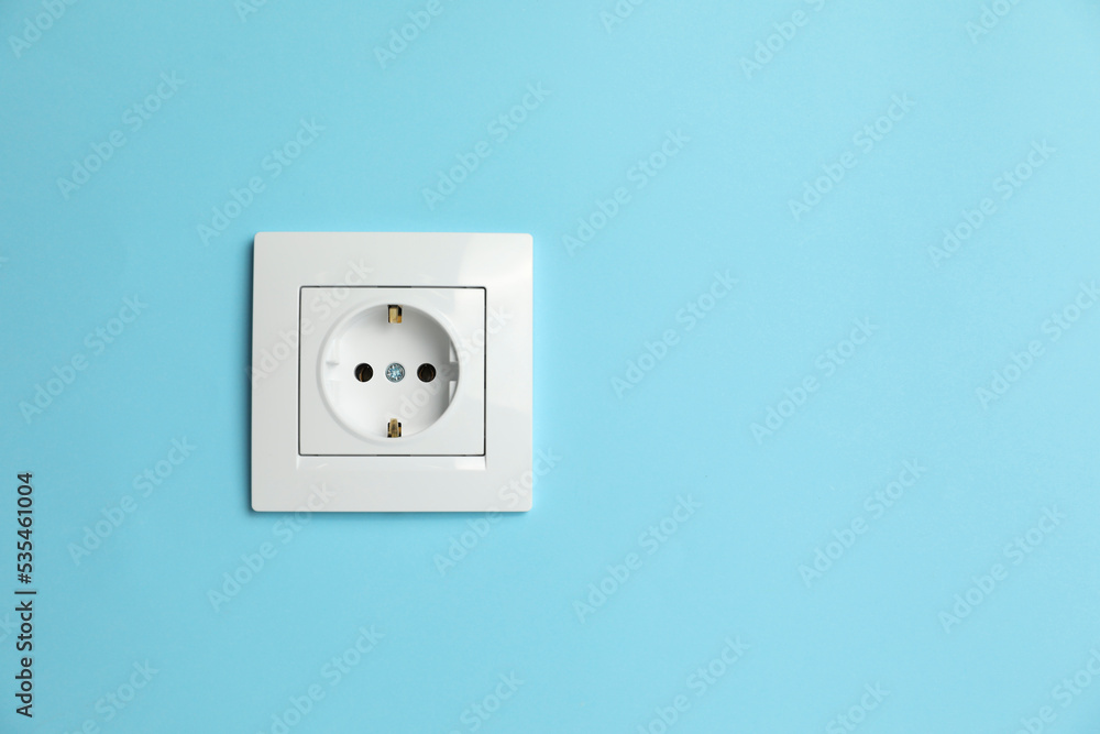 Power socket on light blue wall, space for text. Electrical supply Power socket on light blue wall, space for text. Electrical supply