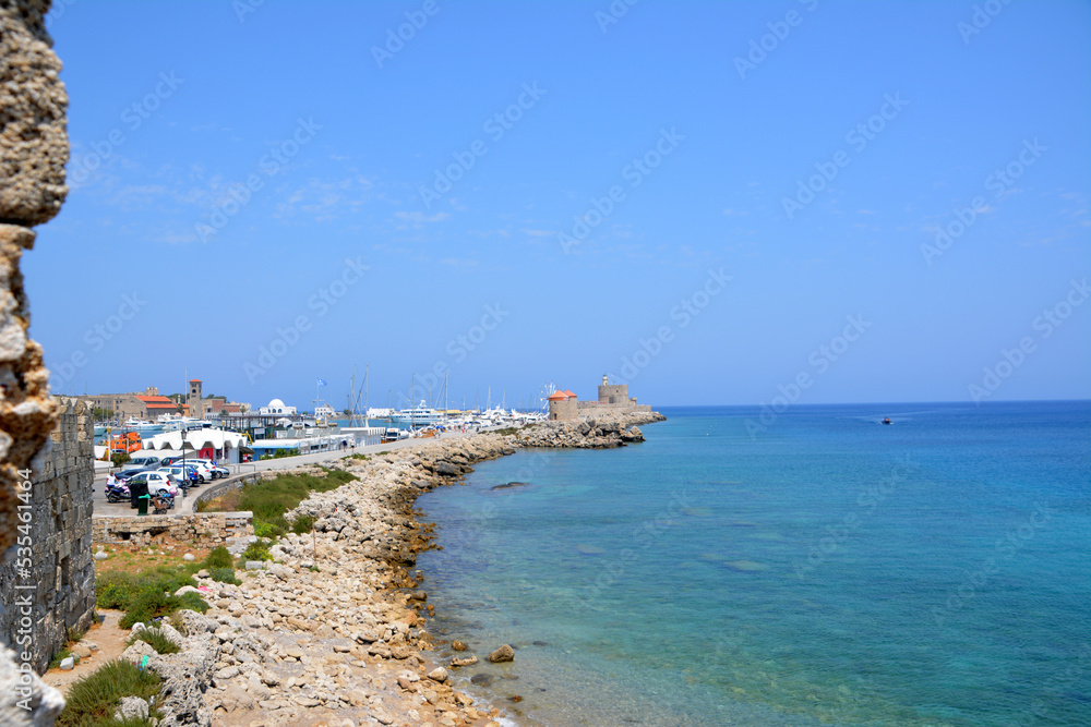 greek coastline with boats and windmills and blue sea and sky