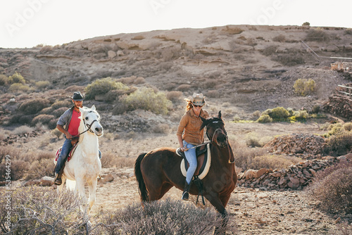 Young couple riding horses doing excursion at sunset - Focus on woman face