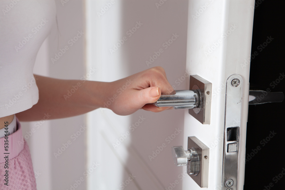 Female hand on metal door handle. Modern interior detail Female hand on metal door handle. Modern interior detail