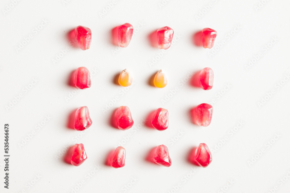 pomegranate and corn seeds isolated composition on white background