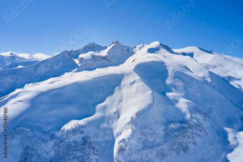 Aerial view of snowy mountains on a sunny day © pridannikov