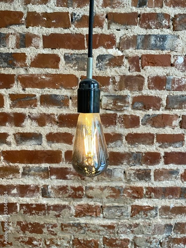 Vertical shot of a light bulb against a vintage brick wall photo