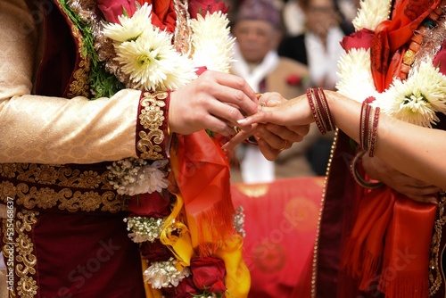 Closeup of a groom's hand putting a ring on a bride's finger during a Nepalese wedding ceremony photo