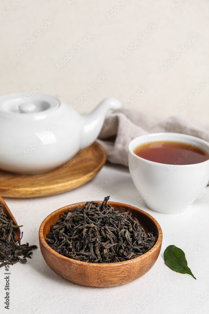 Composition with dry tea leaves and hot beverage on white table Composition with dry tea leaves and hot beverage on white table