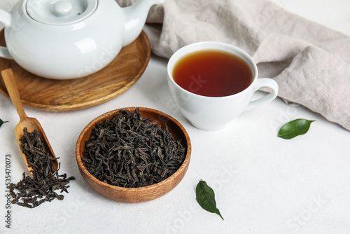 Composition with dry tea leaves and hot beverage on white table