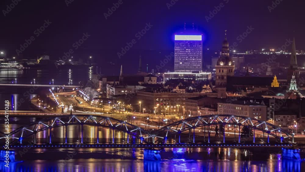 Riga, Latvia. Night time-lapse of traffic in city with bridge in foreground. Riga, Latvia. Night time-lapse of traffic in city with bridge in foreground.