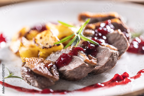 Culinarily prepared duck breast with baked potatoes and cranberry cauce. photo