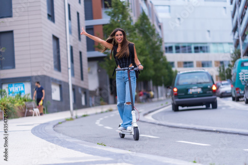 A young brunette woman moving in the city with an electric scooter having fun, along the bike path