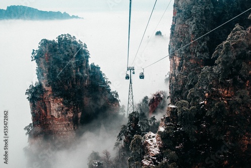 Tianmenshan Cableway view with cottages going and coming through foggy, forested mountains photo