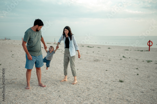 Happy family in the descent. Mom, dad and baby walk along the seashore.