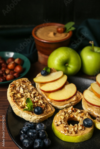 Plate of tasty sandwiches with nut butter, apples and blueberry on wooden table, closeup
