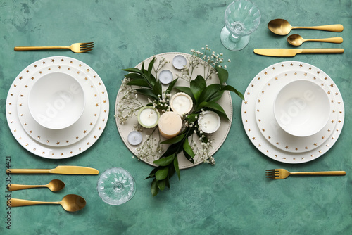 Elegant table setting with beautiful floral decor and candles on green background