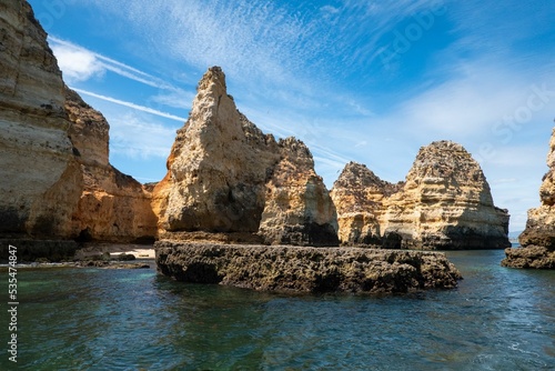 Low-angle shot of a Praia da Boneca with little stone canyons in water and sky background, Portugal
