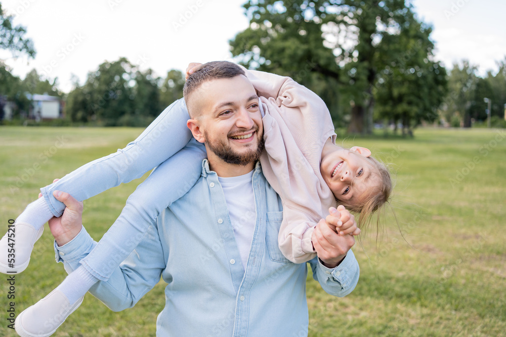 Fototapeta premium Cute and happy little girl spending time with her young loving father while visiting park , they have fun together.