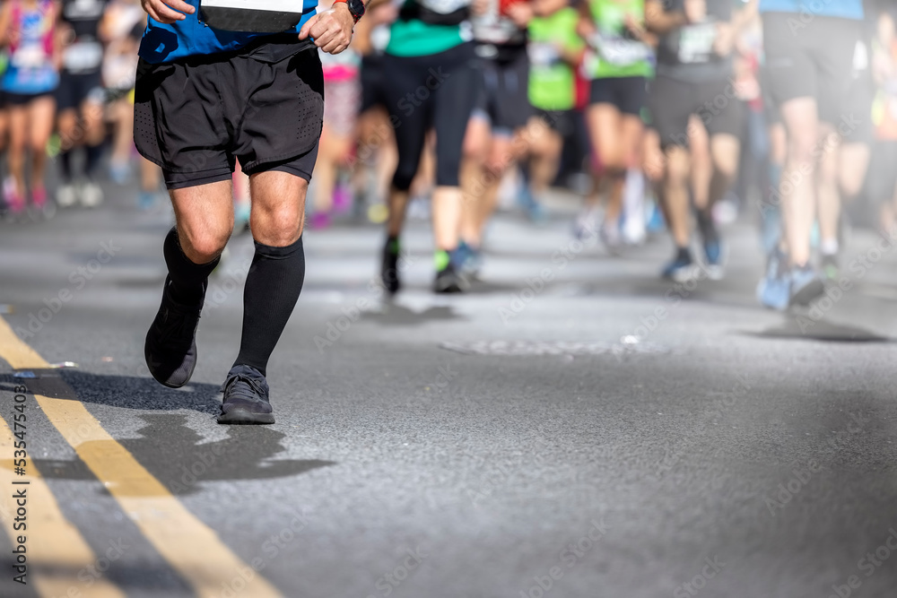 Fototapeta premium Shallow focus view of blurred urban Marathon runners legs on the street with copy spac