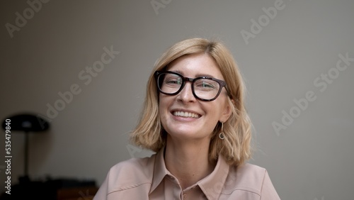 Portrait of blonde woman in eyeglasses smiling. Attractive stylish adult person looking at the camera with sincere and happy smile. Concept of good mood.