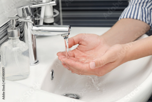 Man using water tap to wash hands in bathroom  closeup