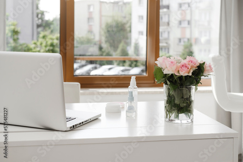 Decorative Cosmetics on the table in empty beauty salon, ordering on-line, making appointment with beautician via Internet on laptop. Nobody. Copy space.