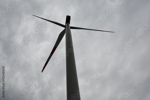 Wind turbine across grey clouds sky