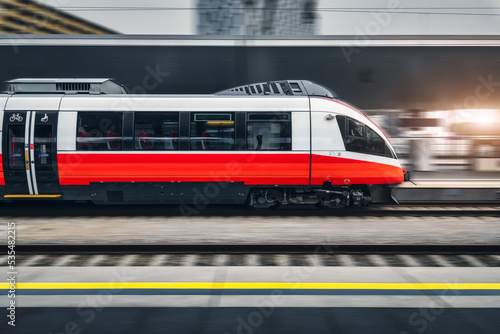High speed train in motion inside modern train station in Vienna. Fast red intercity passenger train with motion blur effect. Railway platform. Railroad in Europe. Commercial transportation. Transport