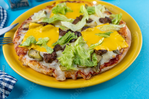 Pizza hamburger with meat shashlik, mustard, lettuce, cheese, sauce. Food in a yellow plate on a blue background. Menu. Homemade pastries. Meal with meat. Food on the table.