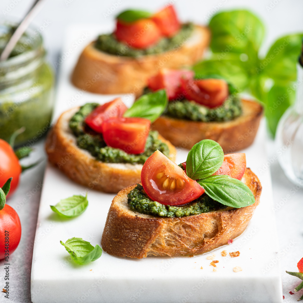 Pesto bruschetta with cherry tomatoes and basil, selective focus Pesto bruschetta with cherry tomatoes and basil, selective focus