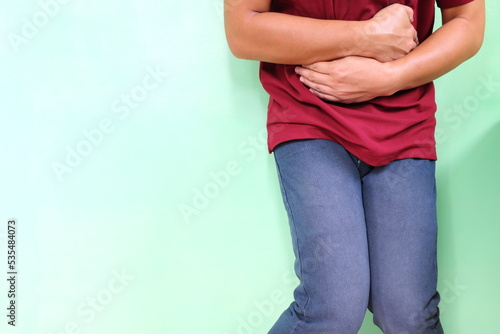 Diarrhea and loose bowel movement concept. Young Asian man holding his stomach area in pain.