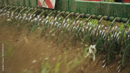 Footage of a green rotary hoeing in the field in motion