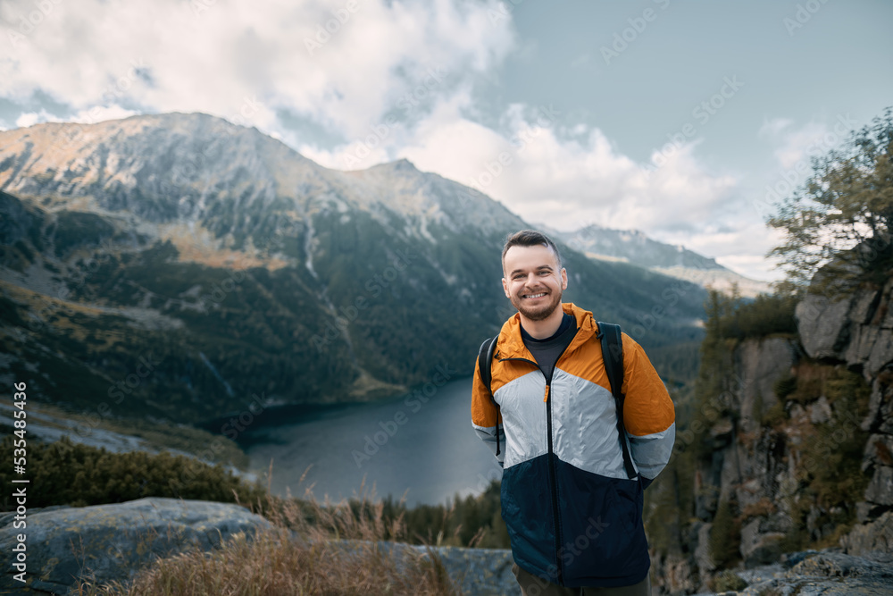 Young beard caucasian man hiking with a beautiful background of mountains, lakes and forests. Concept of active leisure time in mountains.