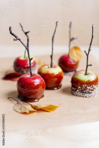 red apples in caramel  sprinkled with nuts  on a light plywood background