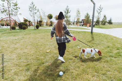 a little girl walks her dog in a city park. a child plays with a Jack Russell terrier outdoors. The concept of pet care