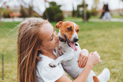 Konstfotografi a little girl kisses and hugs her Jack Russell terrier dog in the park