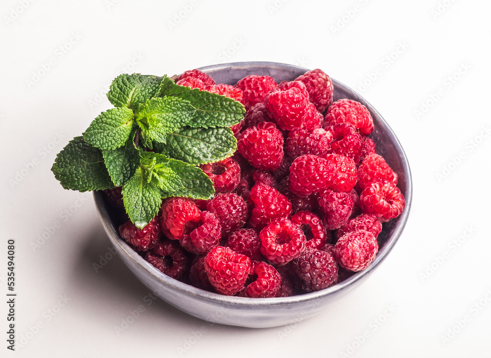 Fresh juicy raspberries in a bowl on a white background.