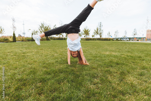 A little girl does gymnastics on the grass. a child does gymnastics in the fresh air in the park.