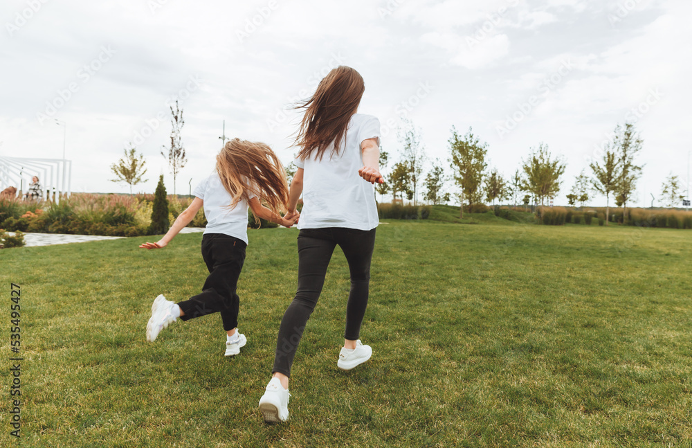 Mother and daughter play and run around the park on a beautiful day. the family is having fun in the park on the grass. morning jog. Mother and daughter play and run around the park on a beautiful day. the family is having fun in the park on the grass. morning jog.