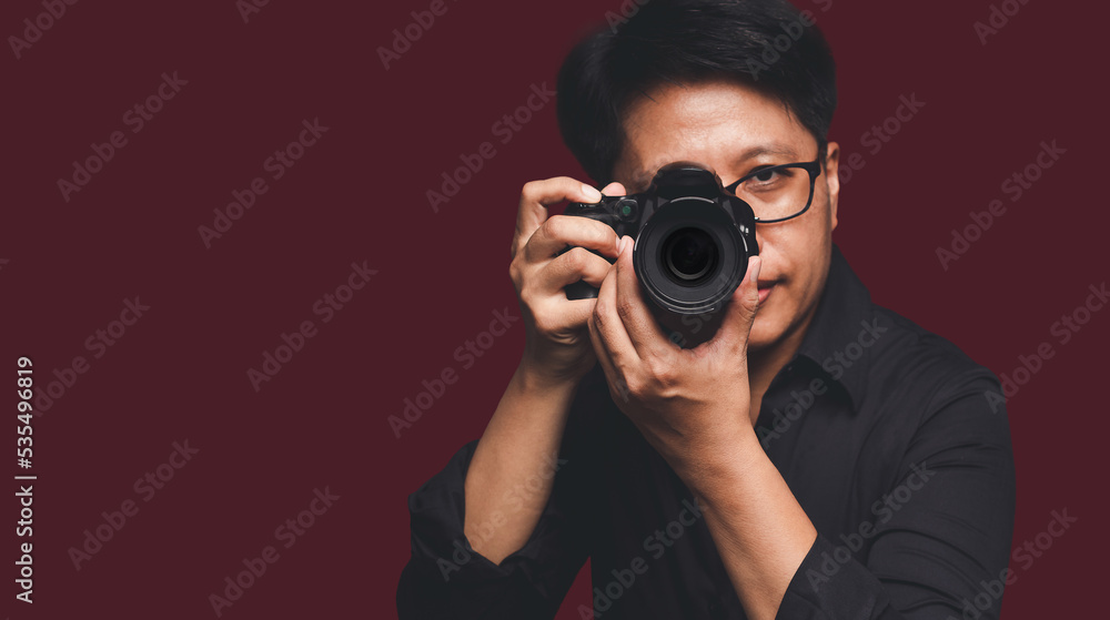 Portrait of a woman with short black hair holding a digital camera while standing on a red background Portrait of a woman with short black hair holding a digital camera while standing on a red background