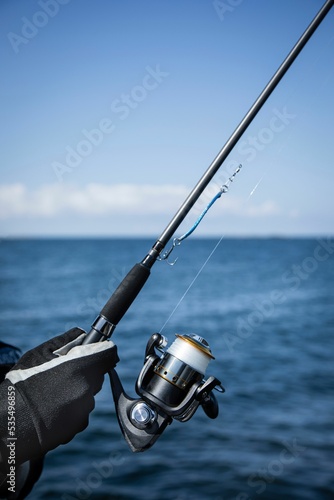 Obraz na plátně Vertical shallow focus shot of human hand in glove golding new fishing rod by th