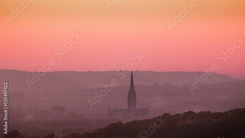 Golden pink sunset sky over Salisbury Cathedral in the hills photo