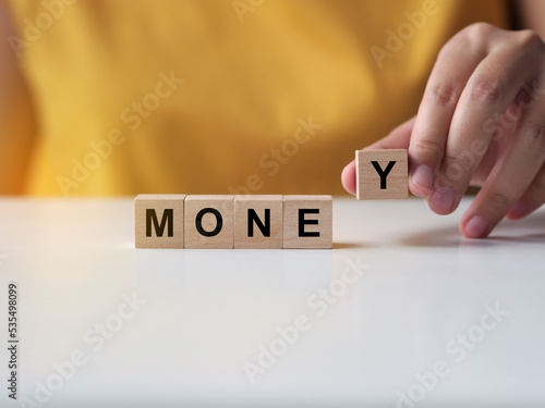 Businesswoman putting a wooden dice to fill the word money. Money management concept.