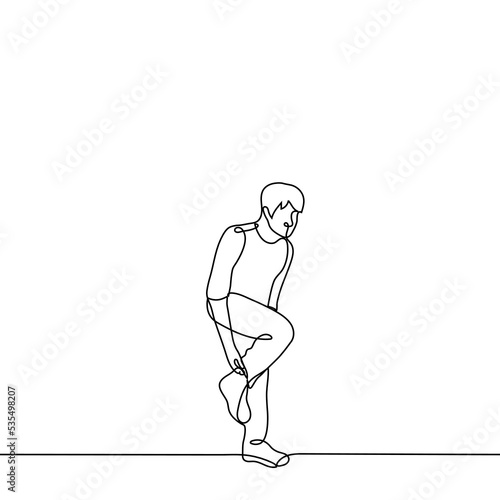 Fototapeta Naklejka Na Ścianę i Meble -  man stands on one leg adjusting his toe on his leg - one line drawing vector. concept to adjust the sock on the go