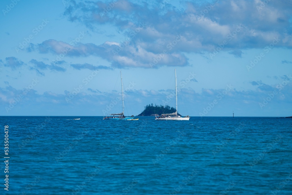 tourist boats and tour boats in the whitsundays queensland, australia. travellers on the great barrier reef, over coral and fish. tourism yachts of young people partying on the water