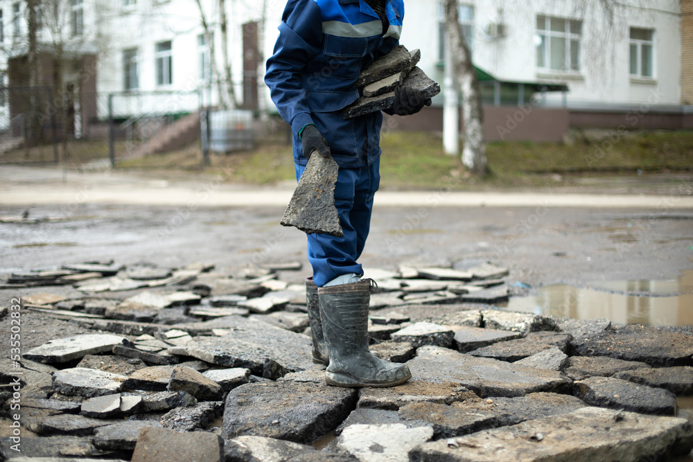 Worker throws rocks at road. Bad road repairs. Builder chooses construction debris.