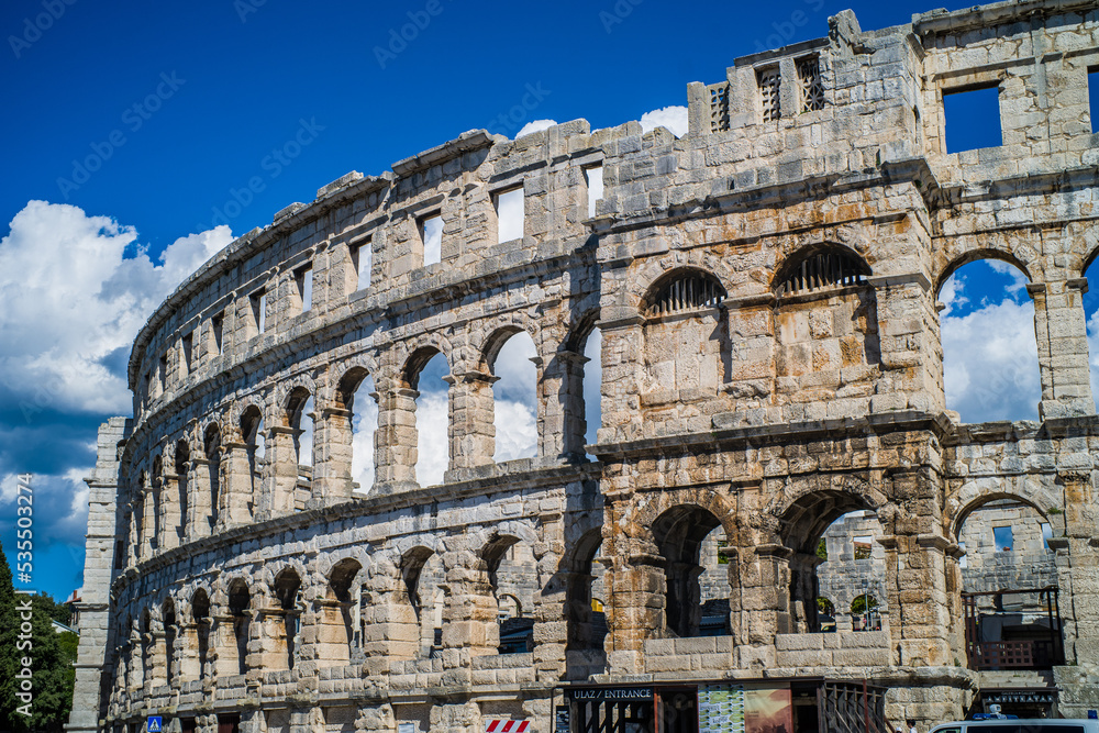 Roman amphitheater in the city of Pula, Croatia. Close-ups on the ancient walls of a Roman building. A beautiful sunny day with fairy-tale clouds in the background