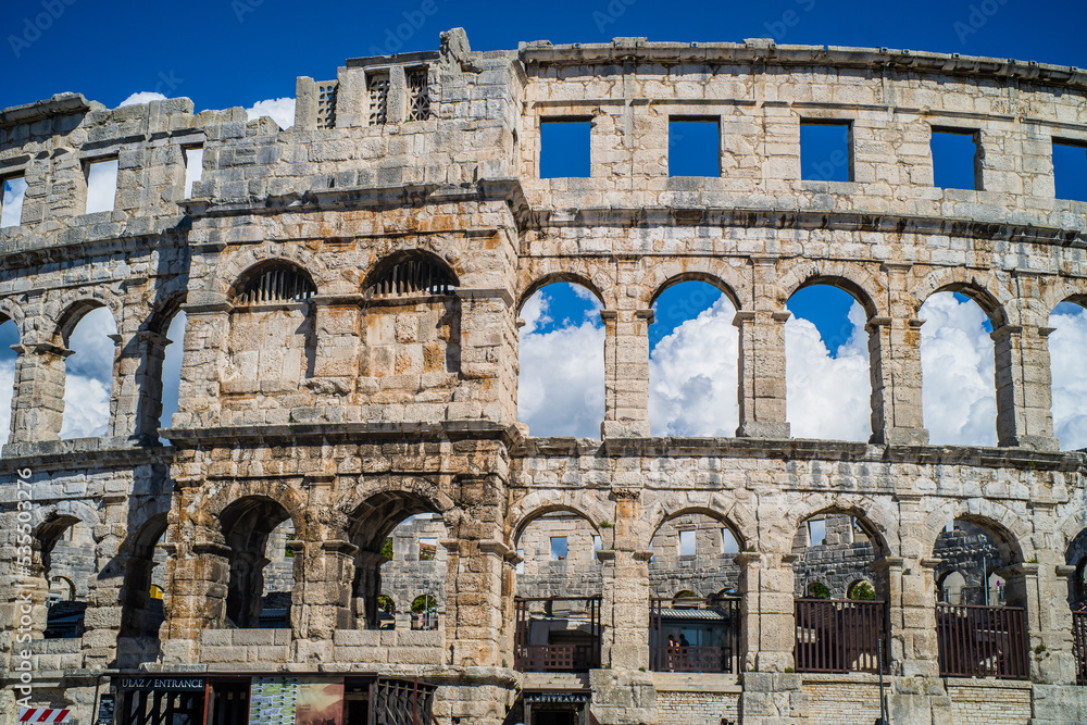 Roman amphitheater in the city of Pula, Croatia. Close-ups on the ancient walls of a Roman building. A beautiful sunny day with fairy-tale clouds in the background